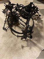 Top view of the Victorian cast iron chandelier showing intricate metal scrollwork and floral decorations.