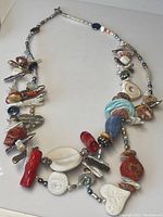 Full view of the vintage necklace with assorted natural elements including coral, conch shells, turquoise, gemstones, and silver beads.