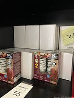 Shelf with boxes of various LED bulbs in white packaging and two boxed packs of 60 watt incandescent bulbs (2 each) in retail packaging.