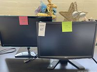 Photo shows two monitors side by side on a white surface. Left monitor is Samsung with slim bezel and silver stand; right monitor is Acer with thicker bezel on a black stand. Both screens are off. Cables visible below the Samsung monitor.
