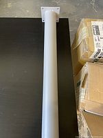 Single steel metal table leg laid on black surface, showing cylindrical shape and mounting plate