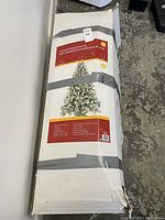 Boxed 7.5ft artificial Christmas tree, showing packaging label with details about size, lighting, and frost finish.