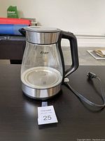 Front and side view of Osler electric kettle with glass body, black handle, stainless steel accents, and measurement markings on the glass container.