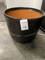 Large black terra cotta pot with visible staining and some chips on exterior.