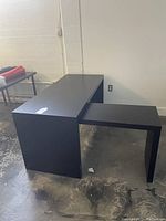 Desk shown with sliding side table extended outward from underneath the main desk, displaying dark wood finish and clean edges.