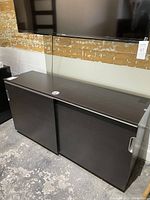 Photo of Ikea GALANT storage unit with both sliding doors closed, showing smooth dark wood finish and metallic handles on sides.