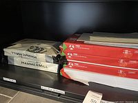 Photo showing 3 red packs of Hammermill 11x17 copy paper and one damaged package of Hammermill paper.