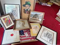 Overview photo showing nine framed art prints and originals arranged on floor, with varying sizes, colors, styles, and frames