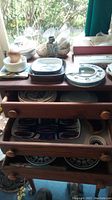 Wooden shelving unit holding various plates, trays, bowls, mortar and pestle