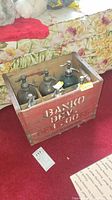 Top and front side view of the vintage seltzer bottles inside a red wooden crate marked 'BANCO B'VE'. Bottles have metal siphon tops and show wear.