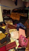 Collection of various handbags, clutches, wallets, and purses in different materials and colors spread on floor