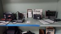 Wide view showing various radios and cassette recorders lined up on a shelf with manuals.