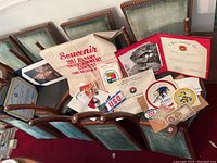 Wide view of collection including souvenir bag, certificates, patches, stickers, and documents laid on chairs.