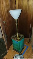 Full view of vintage lamp showing tall brass neck, frosted white glass shade, green metallic base.