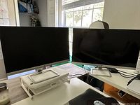 Two HP monitors side by side; the 27-inch on left and the 23-inch on right, both with silver stands.