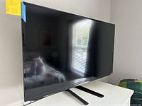 Angled front view of the 43-inch TV on dual-leg stand showing screen and bezel.