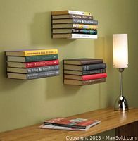 Photo showing three shelves mounted on wall holding books, demonstrating size and use case. Shelves are silver, flat topped, mounted to wall with no visible brackets from front.