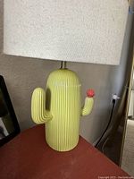 Front view of the green ceramic cactus lamp with white fabric shade, showing pink flower detail.
