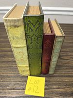 Four decorative book boxes side by side standing upright showing spine designs and heights.