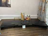 Black multi-section desk organizer, gold metal mesh slot organizer, and jar of highlighters displayed on a wooden surface.