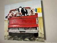 Frontal view of canvas wall art showing a red pickup truck with a black and white cow, a dog, and two pigs in the back against a light sky and green field background.