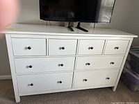 Front view of white Ikea dresser with 8 drawers and black knobs