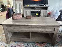Front view of rustic gray wash coffee table with two woven baskets on top and bottom shelf visible.