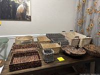 Photo of 11 baskets of various sizes and styles arranged on a table, showing a range of brown and natural wicker colors plus a fabric basket.