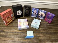 Seven tarot and oracle card decks on a table showing the different box designs and sizes.