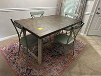 Full set showing rectangular wood table with 4 metal chairs surrounding it, set on patterned rug