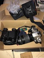 Box containing Canon EOS Rebel G camera with Canon 75-300mm zoom lens, Tasso binoculars with carrying pouch, and multiple manuals and accessories.