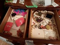 Two open wooden drawers showing mixed jewelry, pouches and watches