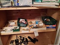 Overview of assorted jewelry in baskets and trays on wooden shelf