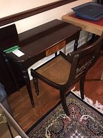Wooden desk and cane seat chair angle showing both items together, highlighting design and condition.