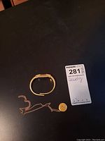 Overview of gold-tone bracelet watch and 10K gold chain with locket on dark surface
