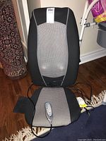 Full view of the Homedics shiatsu and rolling massage seat with remote control attached, showing the black and gray design.