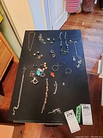 Full view of the 38 pieces of jewelry arranged on a black table showing various types of sterling silver jewelry including necklaces, earrings, brooches, rings, pendants, and bracelet.