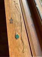 Three necklaces laid side by side on a wood surface showing full chains and pendants.