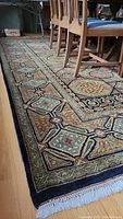 View of rug under dining chairs showing overall pattern and condition