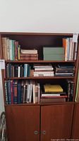Overall wooden bookshelf with three shelves of assorted books