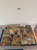 Two trays filled with assorted costume brooches and earrings including Monet pieces, floral, and other designs