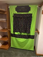 Green hanging fabric puppet theater with black star-patterned curtains and 'Dram's Star Theater' label