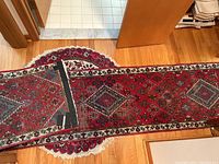 Rectangular runner partially rolled onto round floral medallion rug on hardwood floor