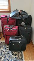 Group shot of four suitcases and one duffel bag on floor