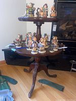 Full view of two-tiered wooden table with pie crust edges and several figurines on top (figurines not included).