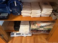 Shelf with white towels, folded quilts, knee braces, and boxes