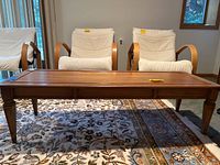 Wide front view of wooden coffee table showing rectangular top and curved armchairs around it.