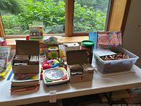 Wide shot of the entire lot showing the Fisher Price cash register, View-Master boxes, various children's books, wooden blocks, and colorful toddler toys on a table.