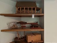 Wooden toy barn with multiple small animal figures inside, wooden spaceship model on side shelf, small wooden box beneath, and small bag of pieces.