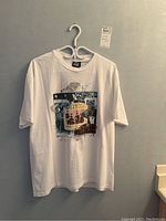 Front view of white Beatles T-shirt hanging on a white hanger with graphic print on chest.
